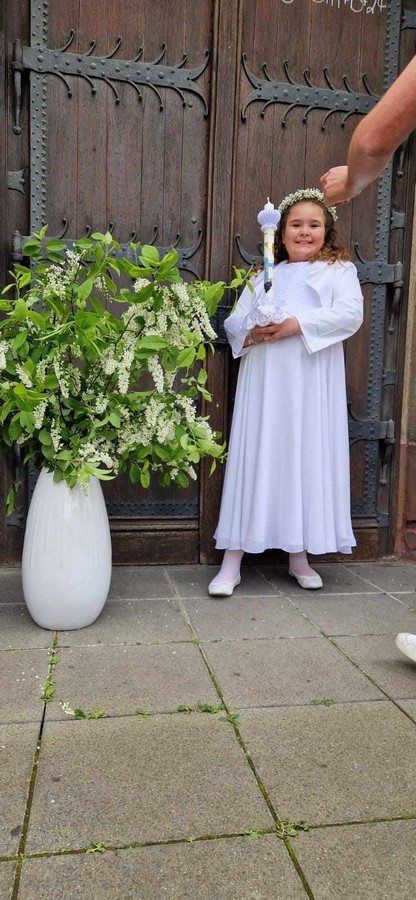 Molliges Mädchen in schlichtem Kommunionkleid mit Bolero