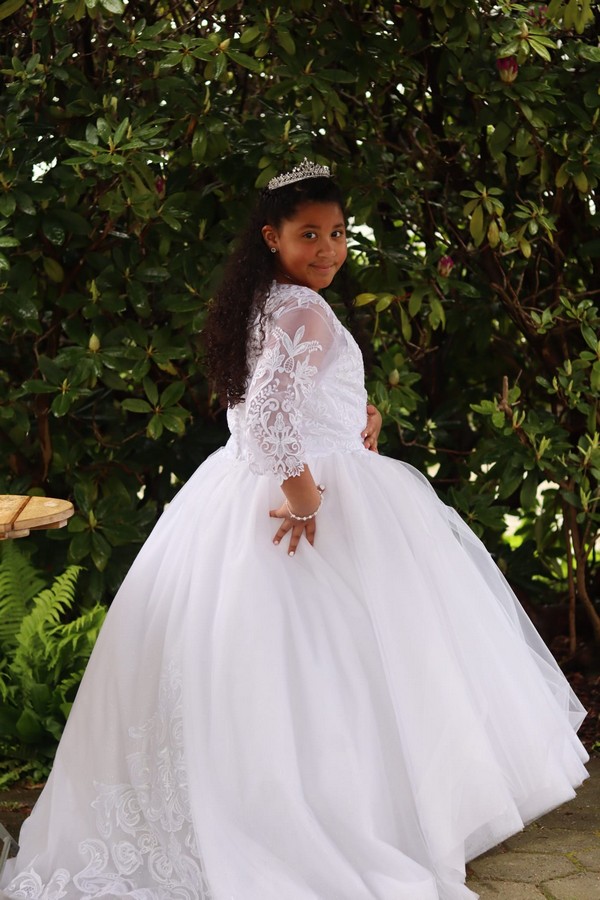 Molliges Mädchen in einem Kommunionkleid mit langen Ärmeln. Italienische Kommunionkleid.