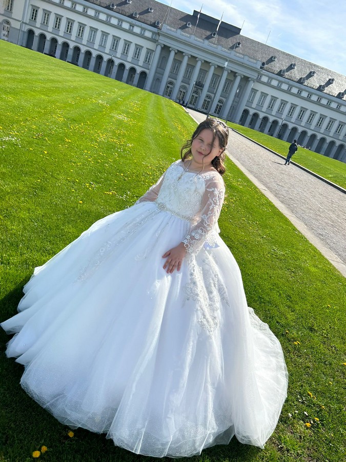 Kommunionkind mollig in einem Kommunionkleid mit langen Ärmeln. Italienische Kommunionkleid.