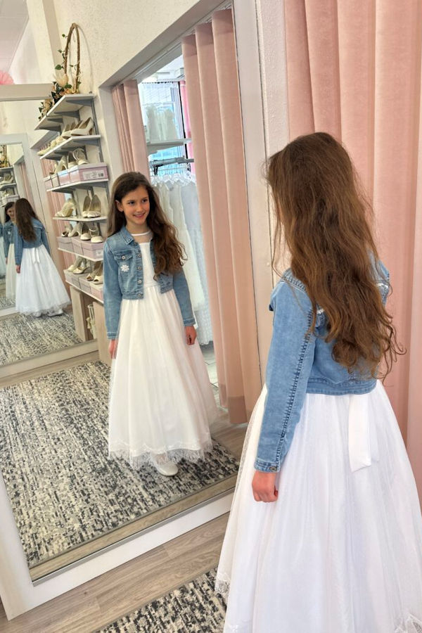 Kommunionkind, das zum Kommunionkleid eine Jeansjacke trägt