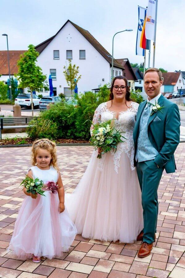 Richtiges Brautpaar mit Tochter im Blumenmädchenkleid.