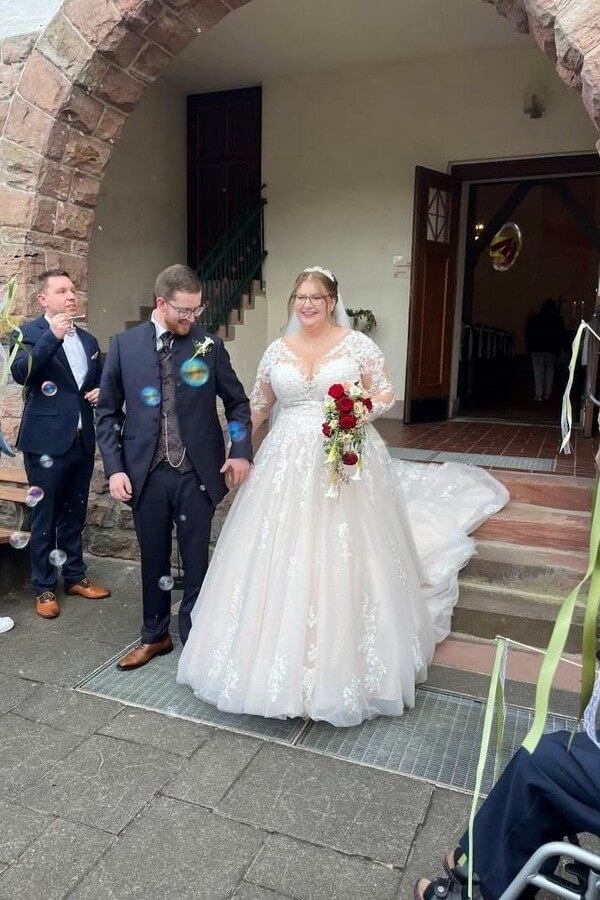 Curvy Braut trägt romantisches Spitzenbrautkleid mit langen Ärmeln aus der Kollektion Miss Emily von Tres Chic – Brautkleid in Übergröße bei Biancas Brautmoden