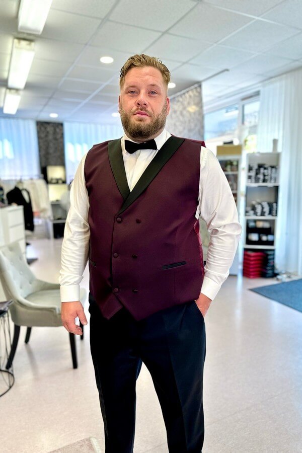 Bräutigam in Übergröße trägt bordeauxroten Smoking mit schwarzem Revers – festliche Herrenmode bis 7XL bei Biancas Brautmoden