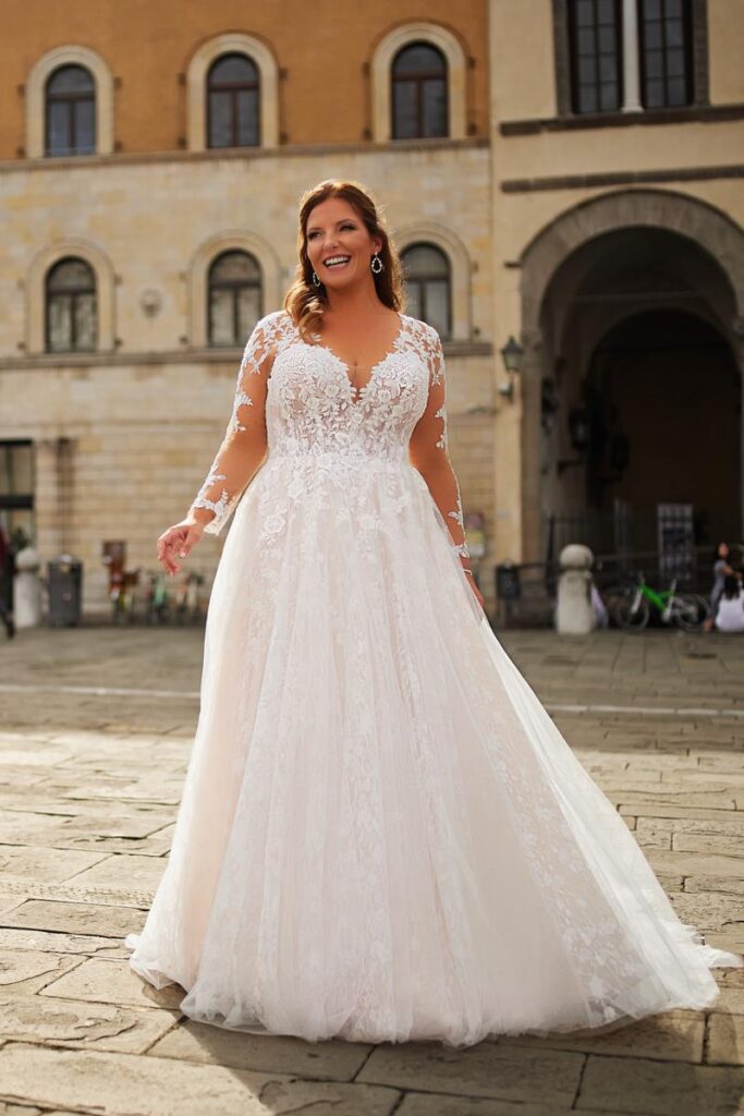 Plus Size Brautkleid von Tres Chic in A-Linie mit Spitzen-Corsage, langen Ärmeln und tiefem V-Ausschnitt von Bianca’s Brautmoden