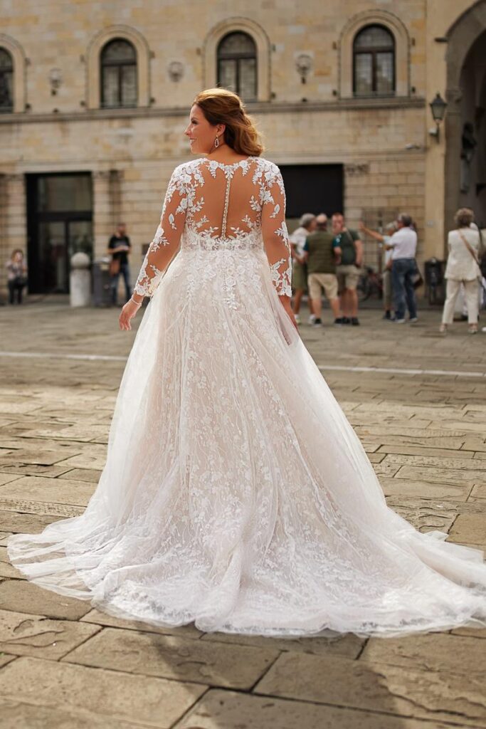 Brautkleid in großen Größen 2026 mit transparenter Rückenpartie aus Spitze, langen Ärmeln und Schleppe von Bianca’s Brautmoden"